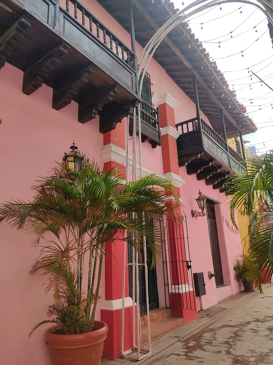 Calle del Casco Histórico con la Casa Rosada, sus balcones de madera y una palmera en matero junto a la entrada